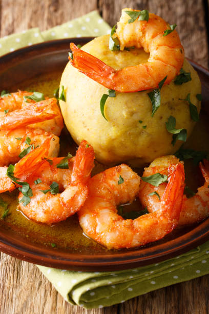 istock Mofongo (Garlic-Flavored Mashed Plantains): a very tasty dish served with shrimp close-up on a plate. Vertical 1155723455