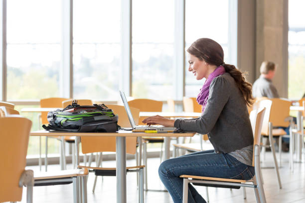 istock Happy, smiling young woman female college university student studying using laptop computer on campus 1155724562