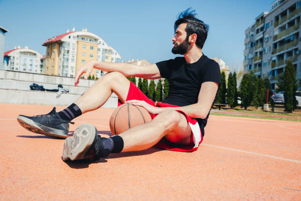 istock Young man sitting on basketball court 1155728342