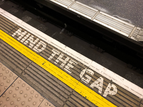London, UK - Mar 20, 2019: Mind the gap written at the edge of the boarding area at the Train station late in the day.