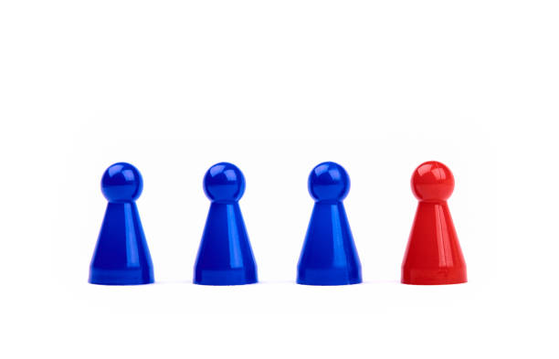 istock Three blue game pieces and a red figure standing next to them as a leader, boss or different. Blurred black and white background. 1155730557
