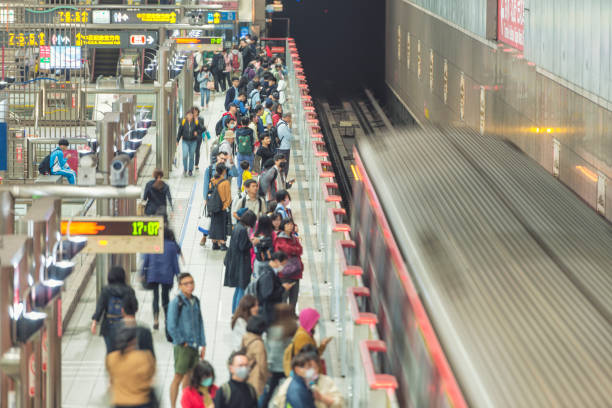 Horizontal long exposure color image of passengers embarking en leaving the metro at Chiang Kai-shek Memorial Hall metro station in Taipei. Passengers are waiting during rush hour.