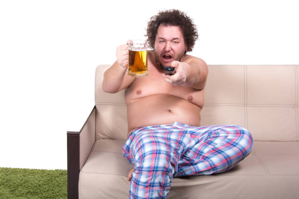 istock Funny fat man watching tv at home. 1155732831
