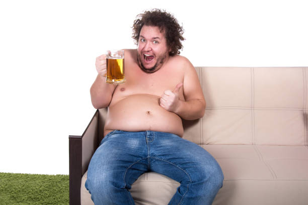 istock Funny fat man watching tv at home. 1155732944