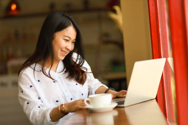 istock Asian woman using  laptop working and drink coffee in cafe 1155733274