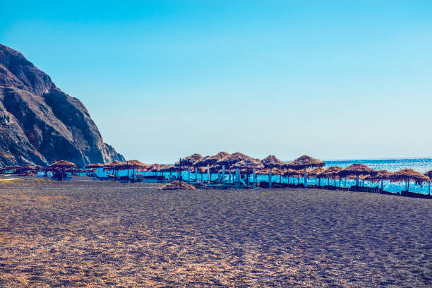 istock Sandy Beach And Umbrellas In Santorini, Greece 1155735158