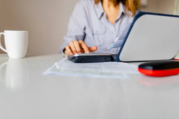 istock Close up of woman using calculator while going through home finances. 1155738970