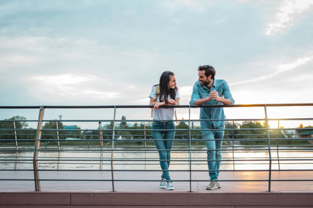An asian adult couple is walking on a sea wall. They are holding hands each other.