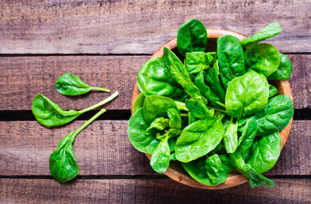 istock Fresh baby spinach leaves in a bowl on a wooden table. 1155742565