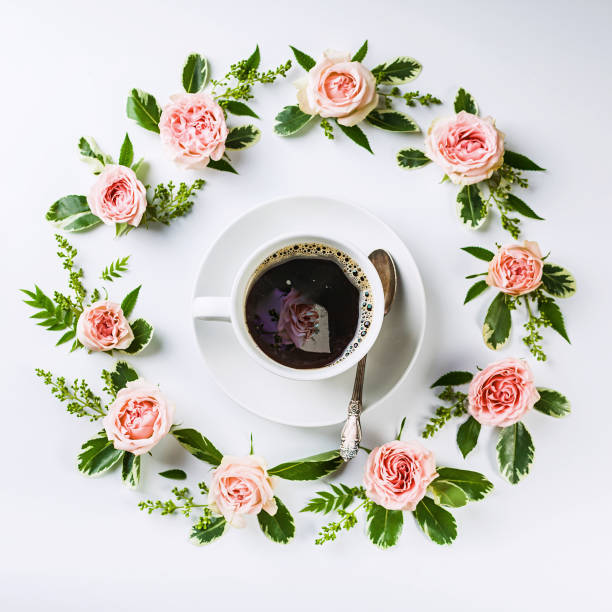 istock Round frame flower pattern of rosebuds on a white background and a white cup of coffee. 1155743724