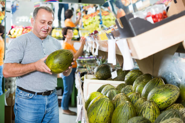 Adult man is choosing ripe melon in the store