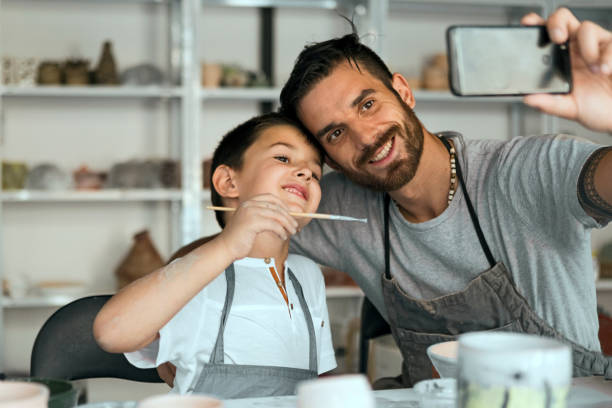 Father and son working on art taking selfie