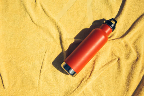 Insulated orange bottle on a yellow towel stock photo