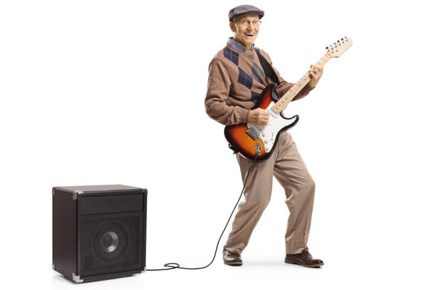Cheerful senior man playing an electric guitar plugged into an amplifier Full length portrait of a cheerful senior man playing an electric guitar plugged into an amplifier isolated on white background amplifier plug stock pictures, royalty-free photos & images
