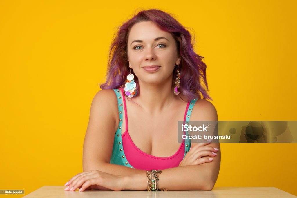 Studio portrait of a 30 year old woman with purple hair on a yellow background 30-34 Years Stock Photo