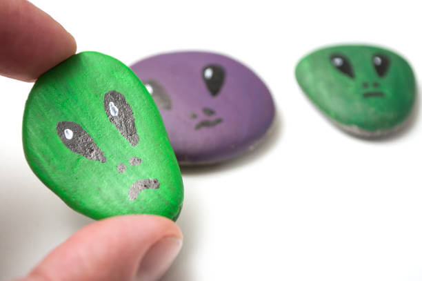 istock colorful aliens painting on stone pebbles in hand on white background 1155760733