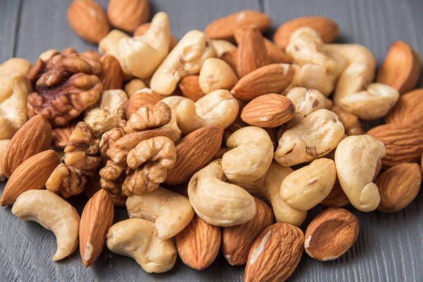 istock Assortment of nuts on gray wooden table. Cashew, hazelnuts, walnuts, almonds. 1155763655