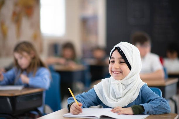 istock Muslim Girl Writing in her Notebook in Class 1155772613