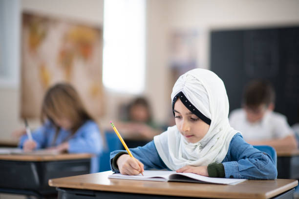 istock Muslim Girl Writing in her Notebook in Class 1155772617