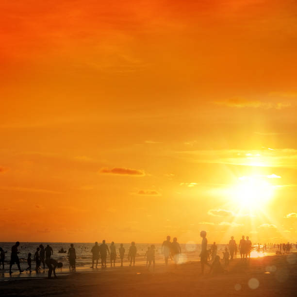 istock silhouetted people on public beach over orange colored sunset sky 1155774470