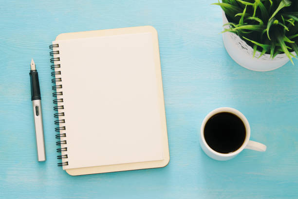 istock Open notebook with empty pages and other office supplies over blue office desk table. Top view 1155775501
