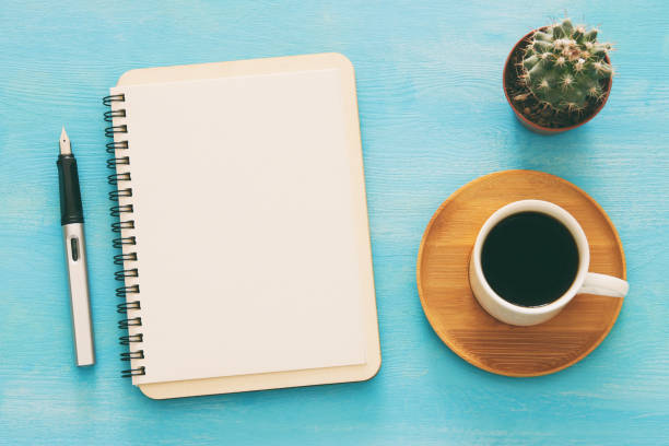 istock Open notebook with empty pages and other office supplies over blue office desk table. Top view 1155775508