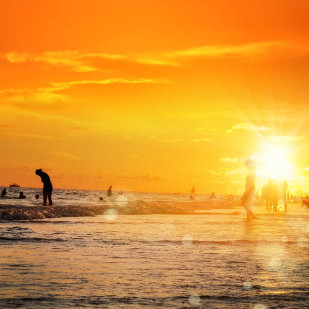 istock silhouetted people on public beach over orange colored sunset sky 1155775998