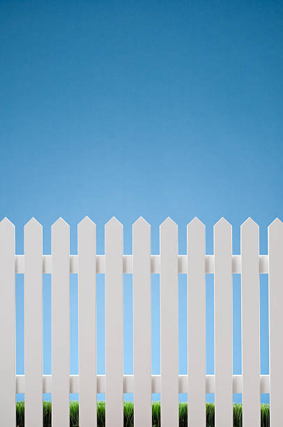 White Picket Fence White picket fence against blue sky with grass in the bottom. Shot in the studio. picket fence stock pictures, royalty-free photos & images