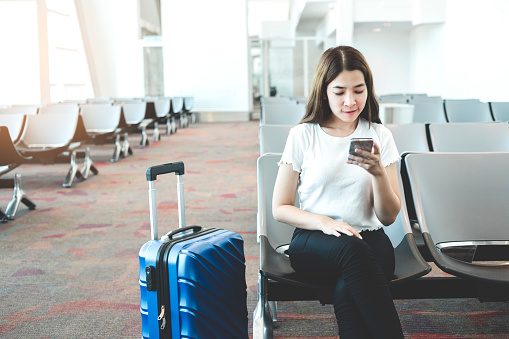 Tourist Women using Phone at international airport waiting for boarding