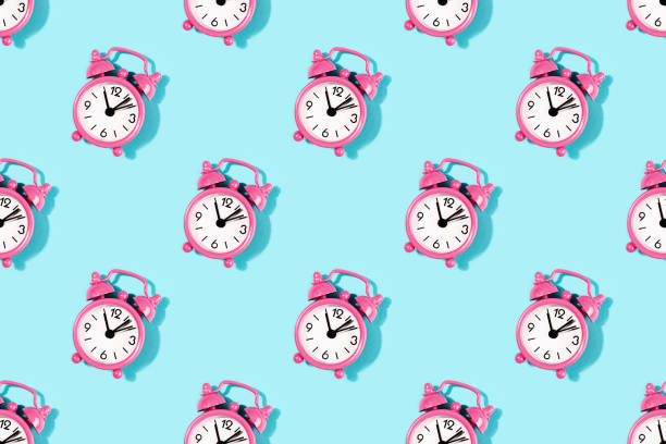 Seamless pattern made with pink alarm clock on turquoise background.