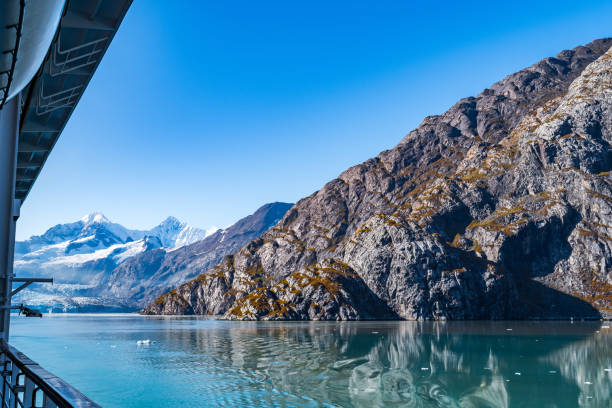 istock Rocky mountain range in Glacier Bay Alaska with ice/snow covered, broken icebergs floating, reflection in water 1155808884