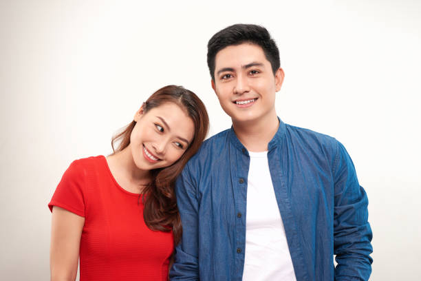 istock young asian couple leaning heads together over white background 1155811009