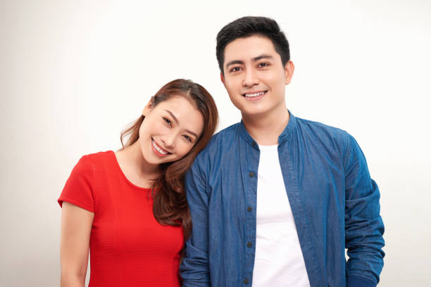 istock young asian couple leaning heads together over white background 1155811101