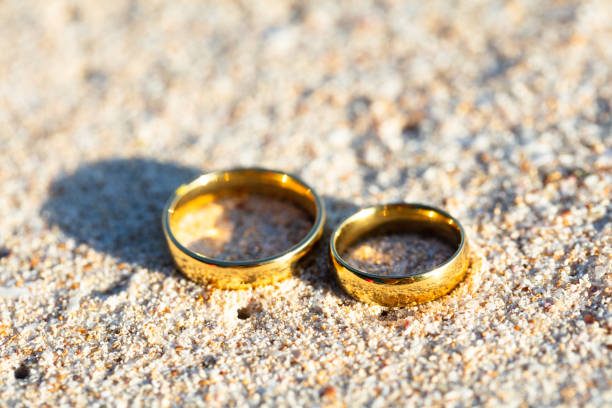 istock Golden And Shiny Wedding Rings On Beach 1155811972