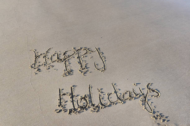 istock happy holidays written on the wet  sand at low tide 1155828349