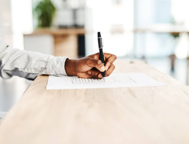 Ticking the boxes that apply to him Closeup shot of an unrecognisable man filling in paperwork at a table form submission stock pictures, royalty-free photos & images