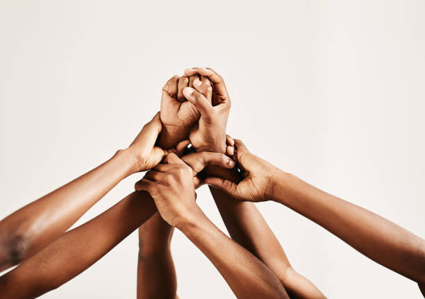 Closeup shot of a group of unrecognisable people holding on to each other's arms