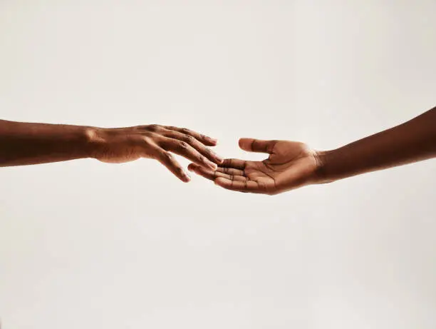 Closeup shot of two unrecognisable people reaching for each other with their hands