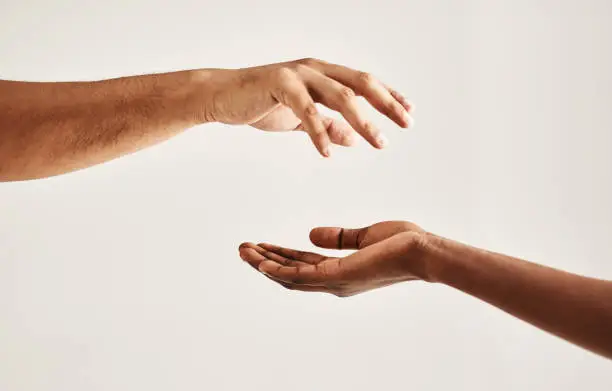 Closeup shot of two unrecognisable people reaching for each other with their hands