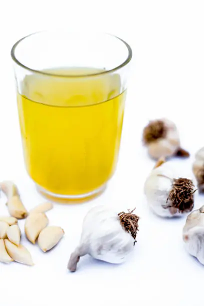 Fresh organic Garlic juice isolated on white along with fresh garlic cloves and garlic bulbs.