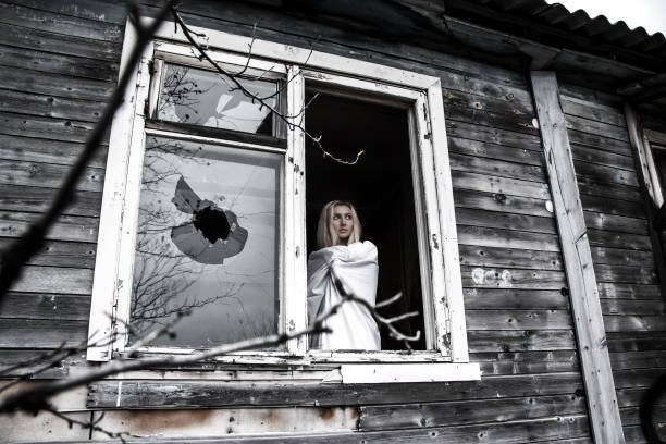 Woman in a white shirt staying near the broken window