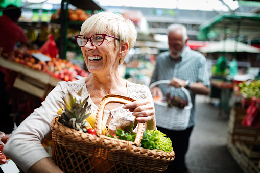 La pareja mayor que compra verduras y frutas frescas en el mercado local photo