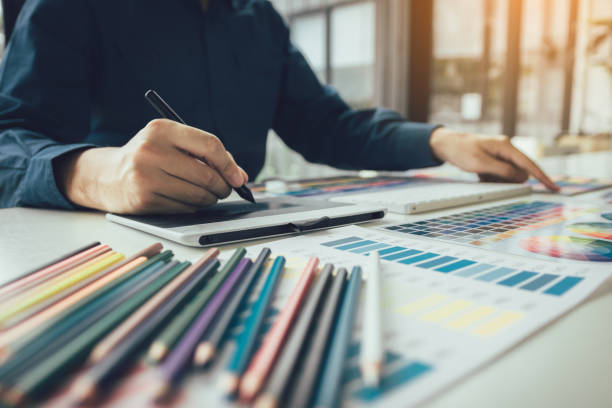 istock Freelance creative designers working on desk using digital graphic tablet and drawing with pen in modern home office. 1155835263