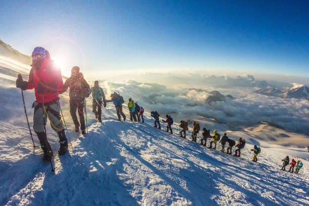 russia, elbrus - 15 luglio 2018: un gruppo di persone scala la montagna elbrus. ogni anno migliaia di persone scalano la montagna più alta della russia e dell'europa - exploration mountain teamwork mountain peak foto e immagini stock