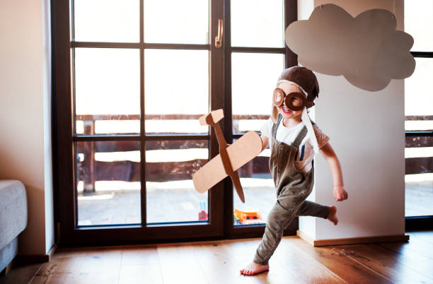 un garçon d’enfant en bas âge avec l’avion de carton jouant à l’intérieur à la maison, concept de vol. - indoor court photos et images de collection