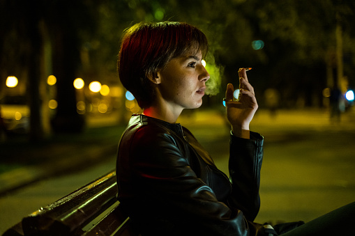 Woman smoking at night in the street