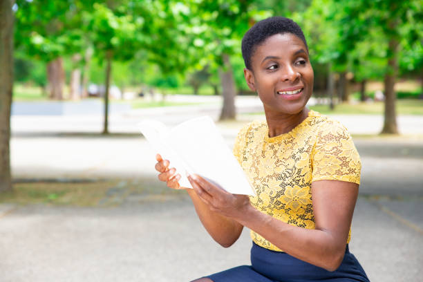 istock Female university student reading book on campus 1155840482