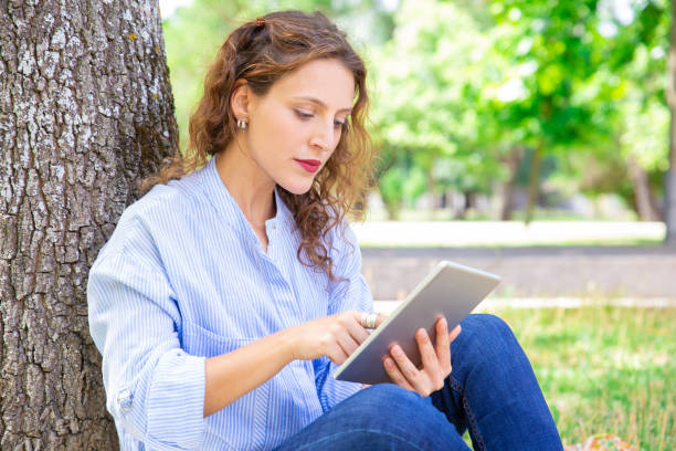 istock Curious young woman reading online article on tablet 1155840491