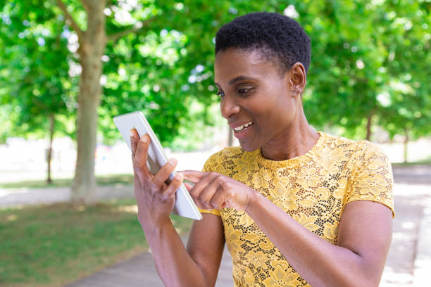 istock Jolly addicted black woman using tablet outdoors 1155840493