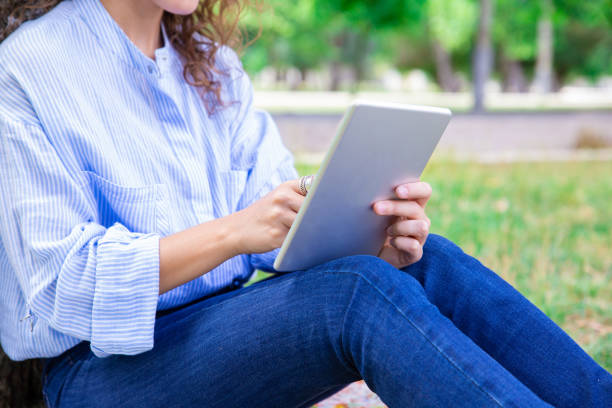 istock Close-up of woman using digital tablet in summer park 1155840495
